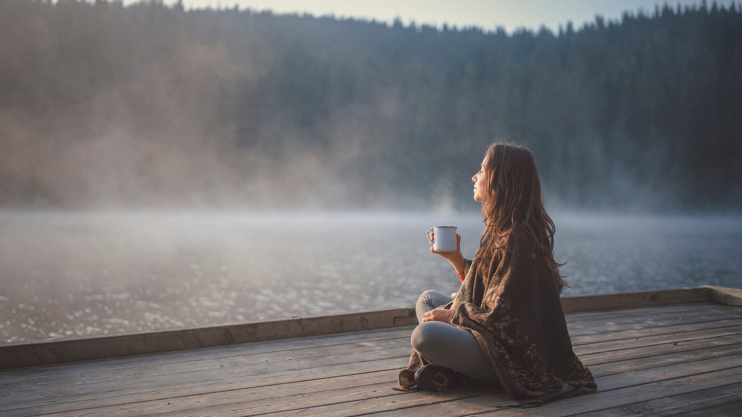 Achtsame Frau entspannt am See und hält eine Tasse - Ziele erreichen und Erfolg durch Achtsamkeit